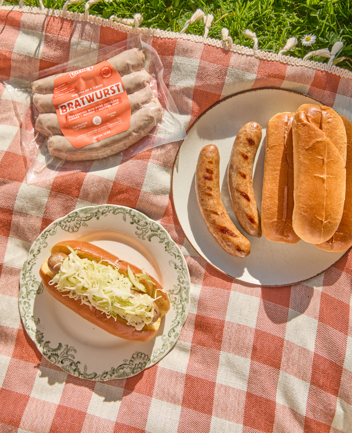 Bratwurst sausages with buns on a checkered picnic blanket