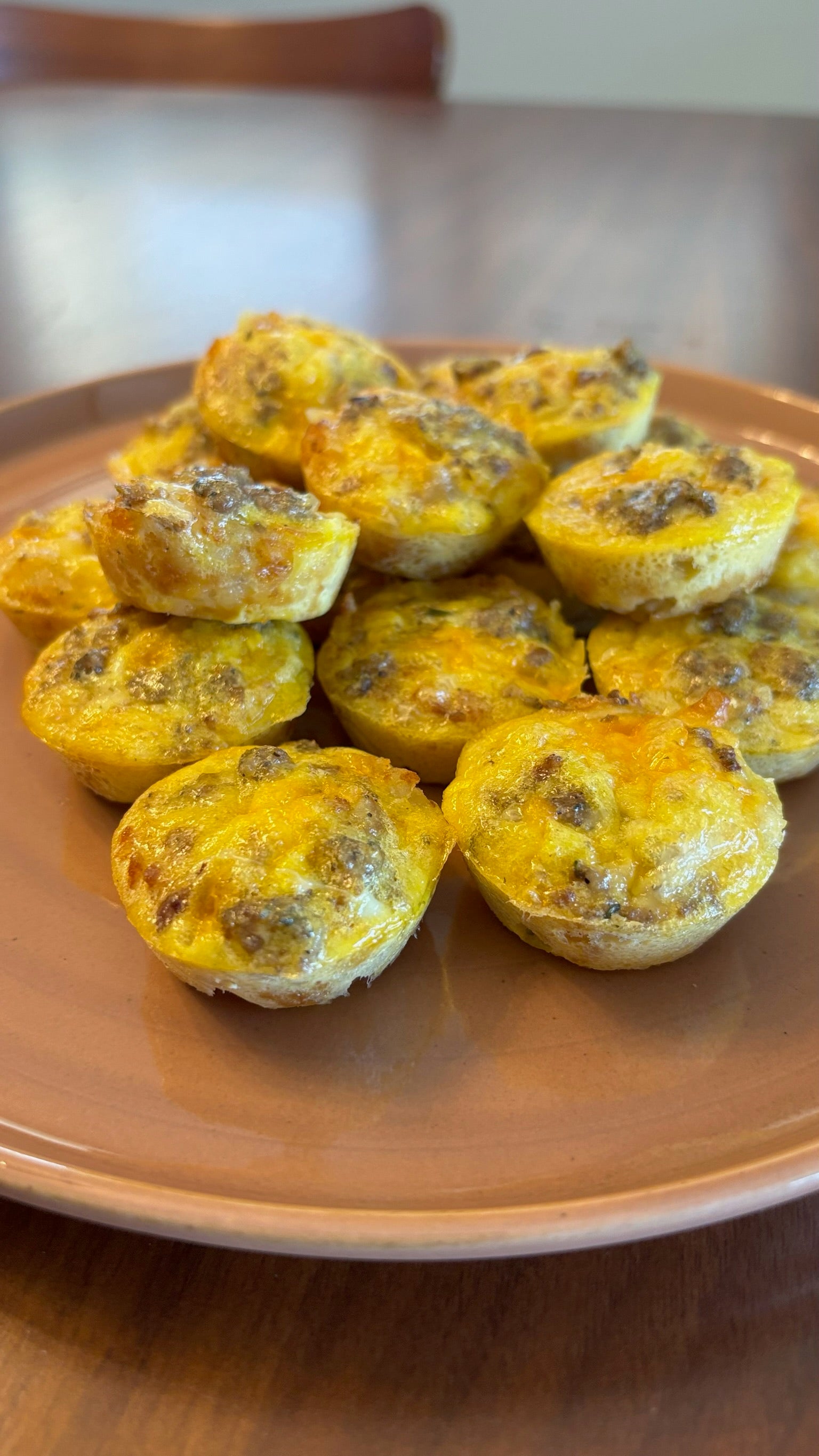 Plate of mini egg & sausage muffins on a wooden table