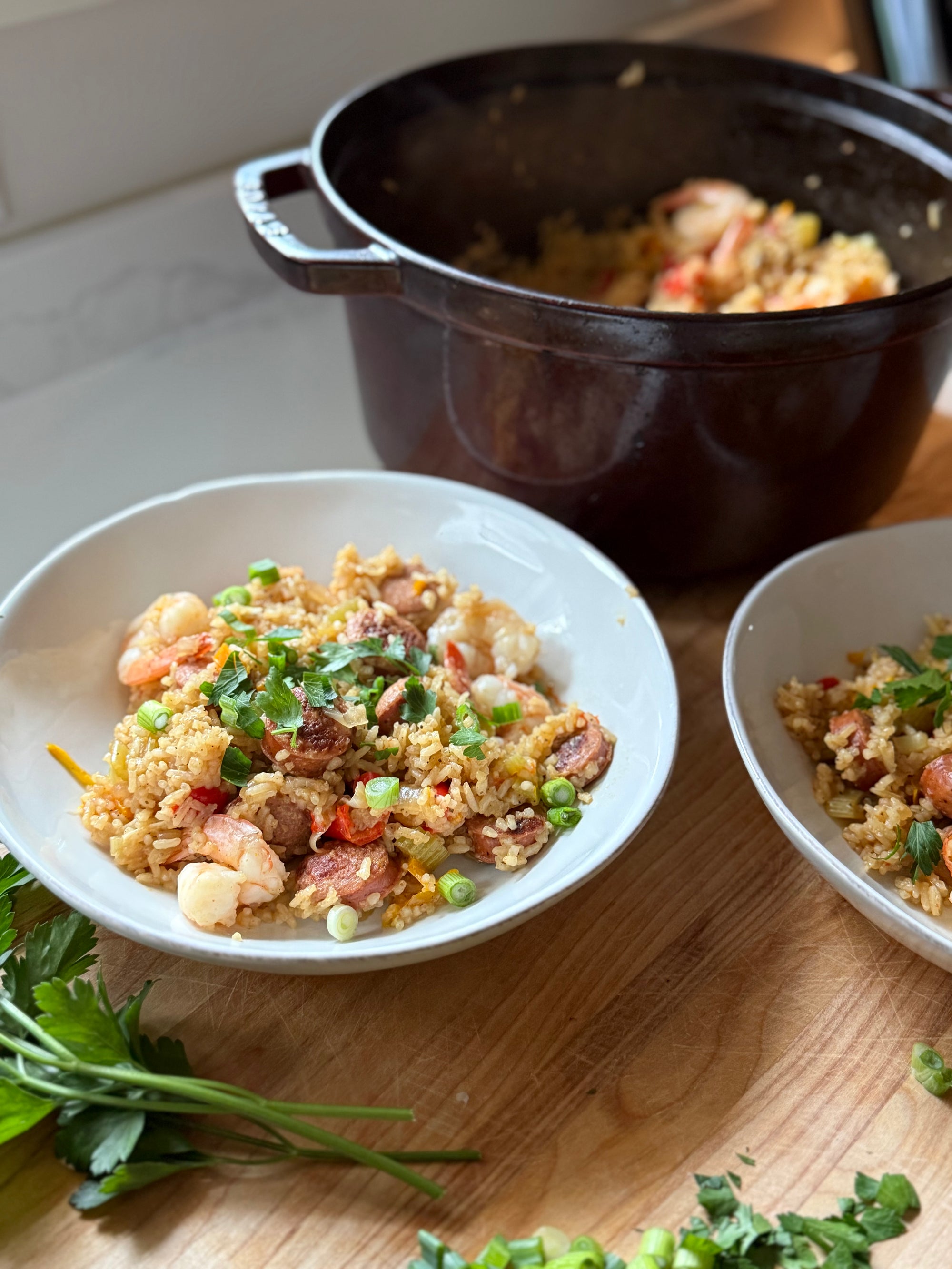 Two bowls of fried rice with vegetables on a wooden surface, with a pot in the background.