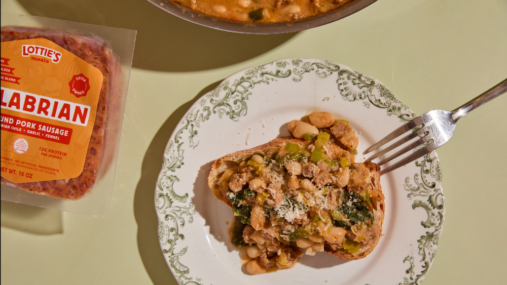 Plate of Calabrian sausage toast and a plate with Lottie's Calabrian packaging off to the side on a table.