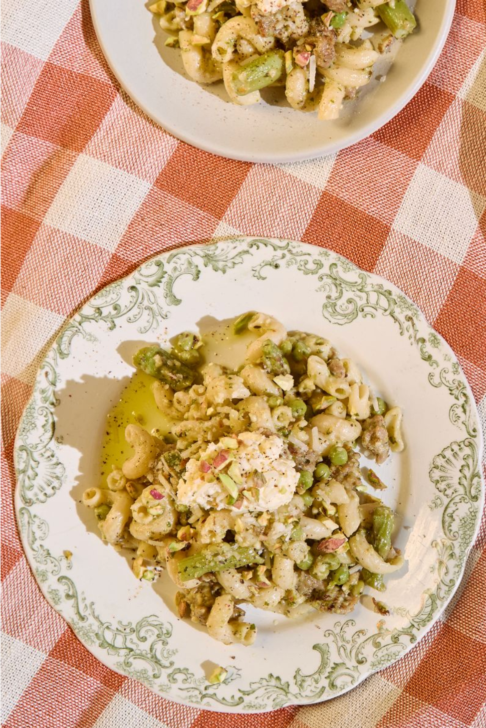 Sausage pasta dish with asparagus on a decorative plate on a checkered tablecloth