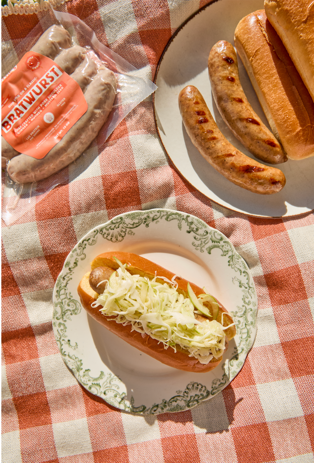 Grilled sausages on buns with coleslaw on a checkered tablecloth
