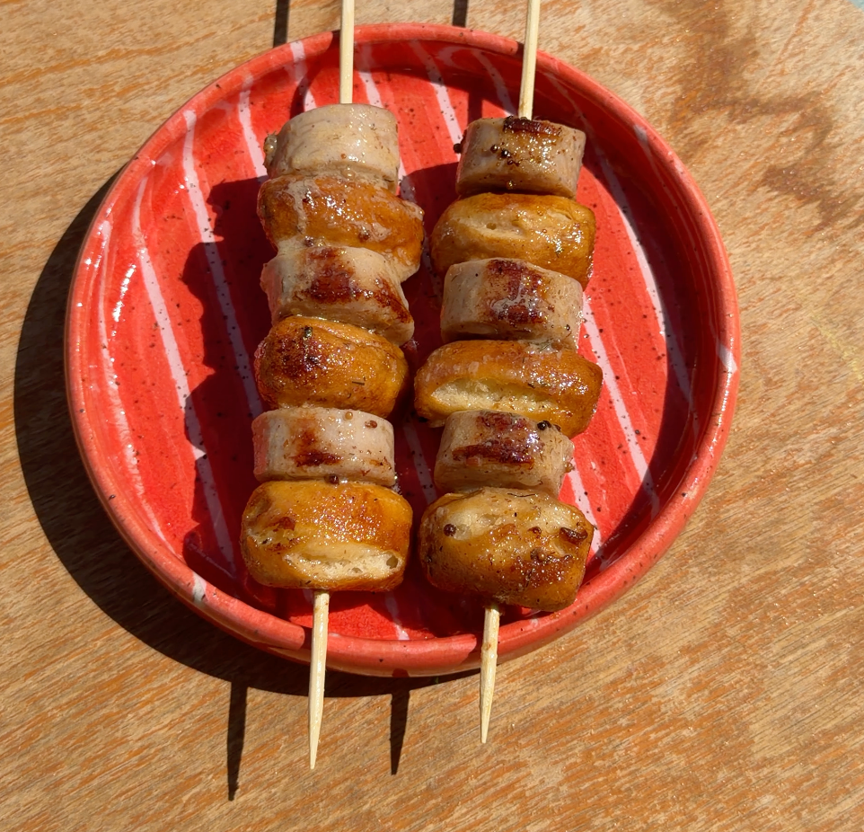 pretzels and bratwurst on a skewers on a red plate on a table